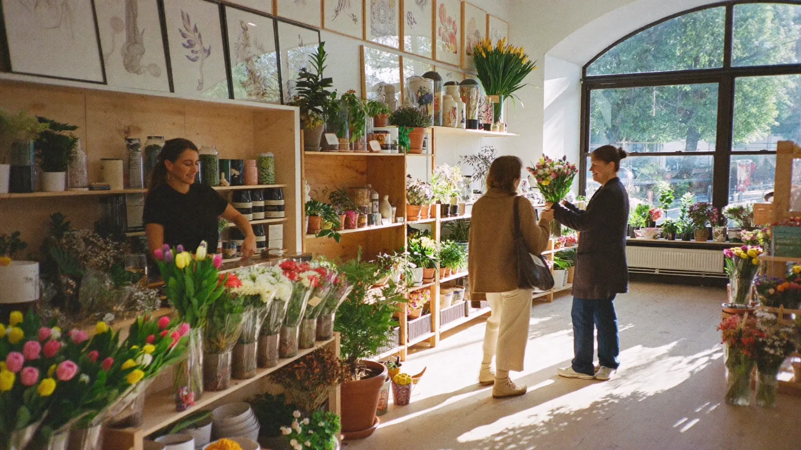 Blomster- och inredningsbutik full av växter där kunder tittar bland hyllorna