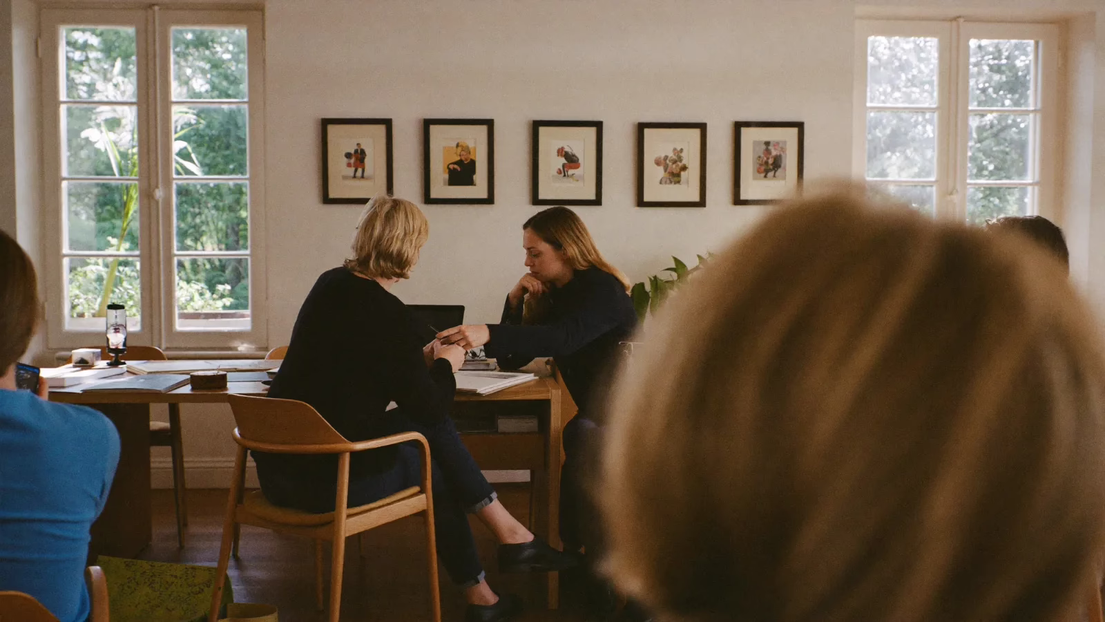 Vy över axeln på en person vid ett skrivbord medan en kollega lutar sig in och pekar