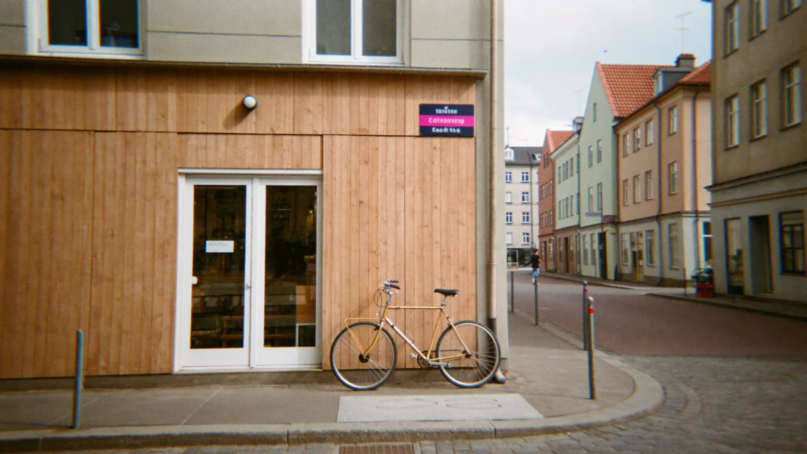 Nordisk gata med en liten butiksfasad i trä och en cykel lutad mot väggen