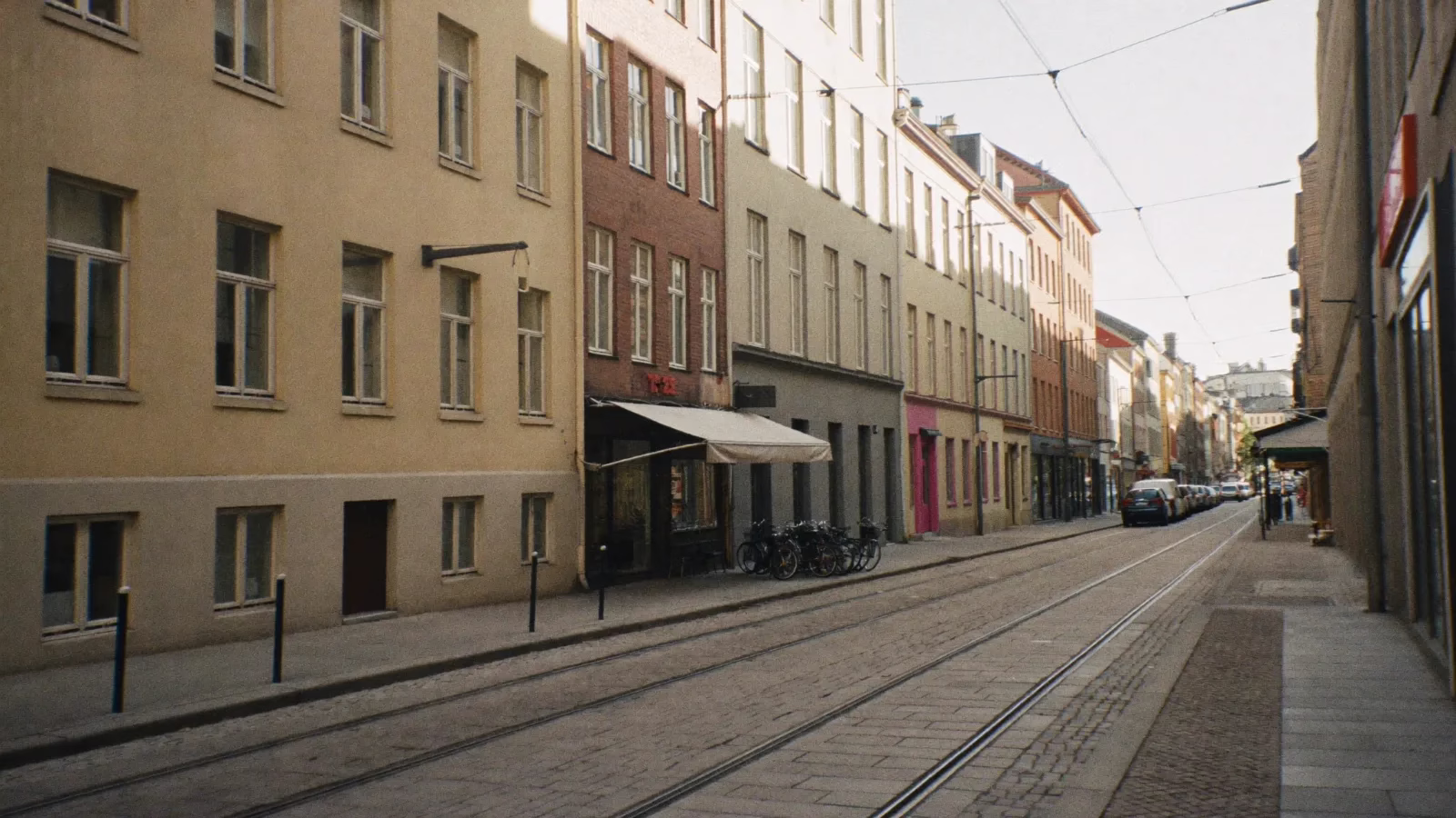 Gata i Göteborg med spårvagnsspår i gatstenen och små butiksfasader med markiser